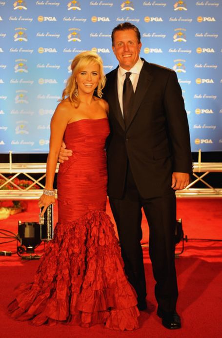 phil and amy on the red carpet, phil wearing a black suit, amy wearing a red strapless mermaid gown 